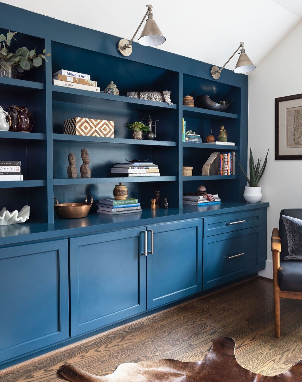 Wondering what to do with an awkward angled ceiling? Turn a challenging space into smart, functional storage. Custom built-ins with bookshelves on top and deeper cabinets below take advantage of every square inch. Decorative hardware and angled light