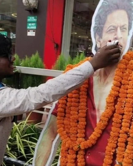 Fan feeds prasad (cake) to a cutout of Shah Rukh Khan, 2023, Pandua, West Bengal.