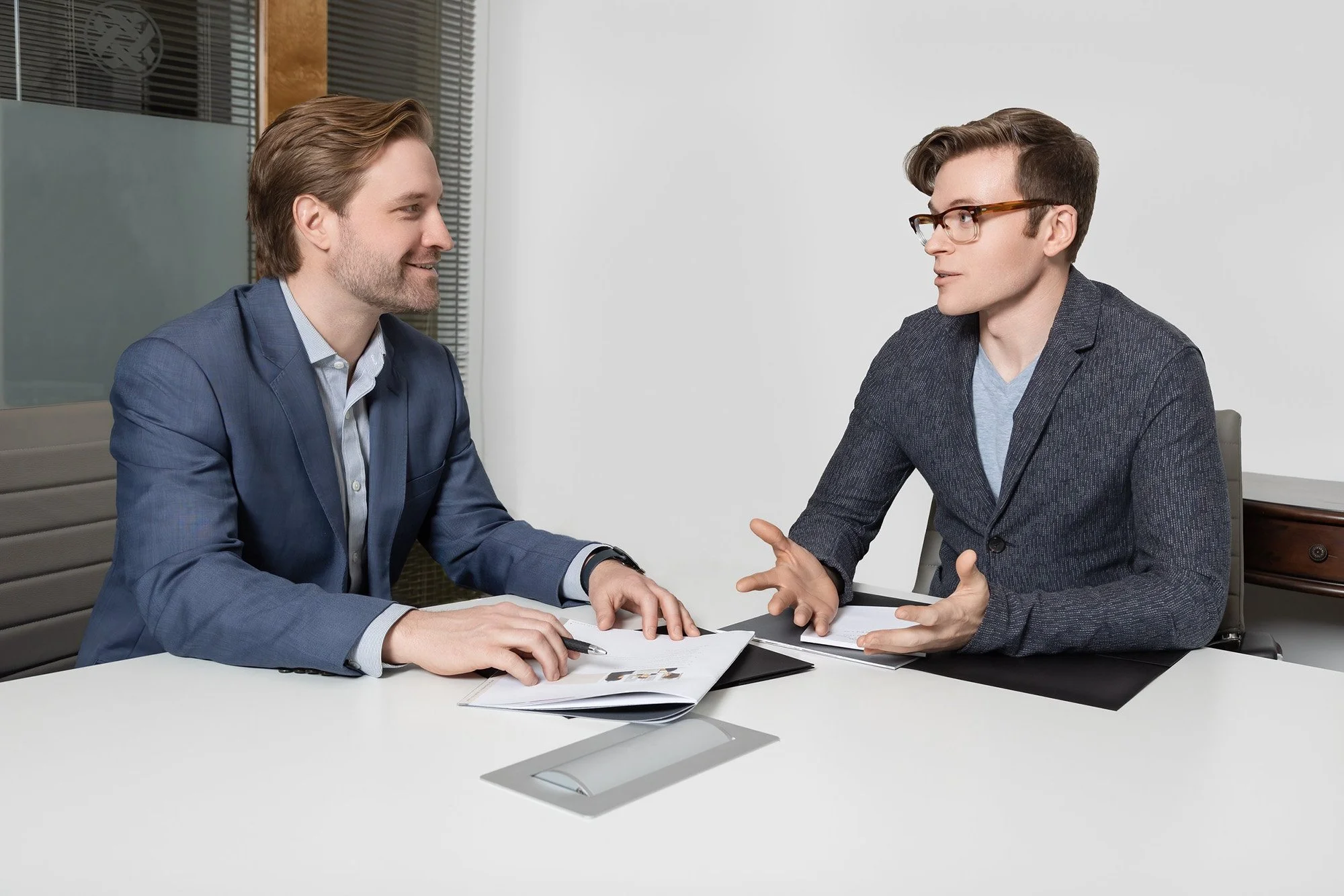 Private Wealth Management - Cornerstone Wealth Advisors. Two men in business attire having a discussion in an office conference room.