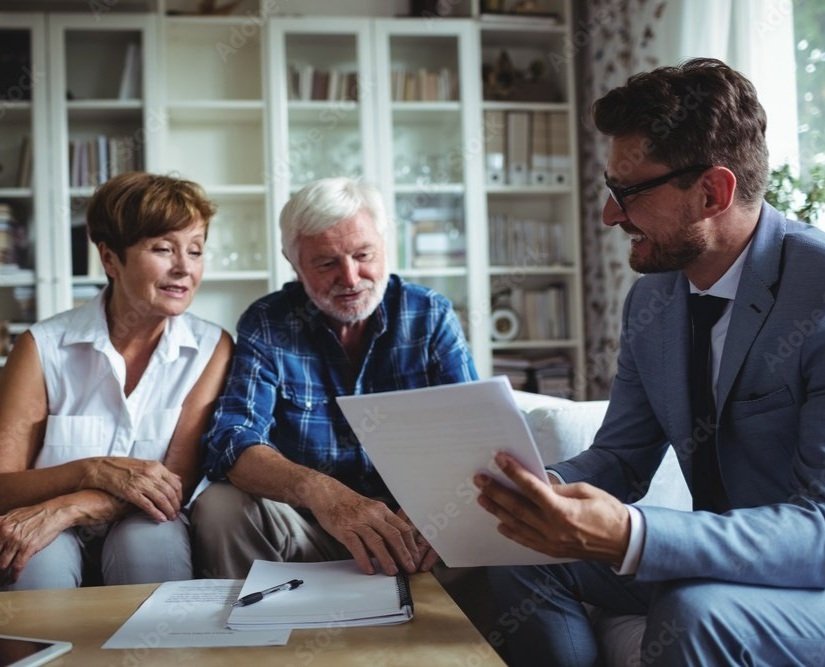 A family meeting with an older woman, an older man, and a younger man in a living room, discussing documents with a financial advisor.