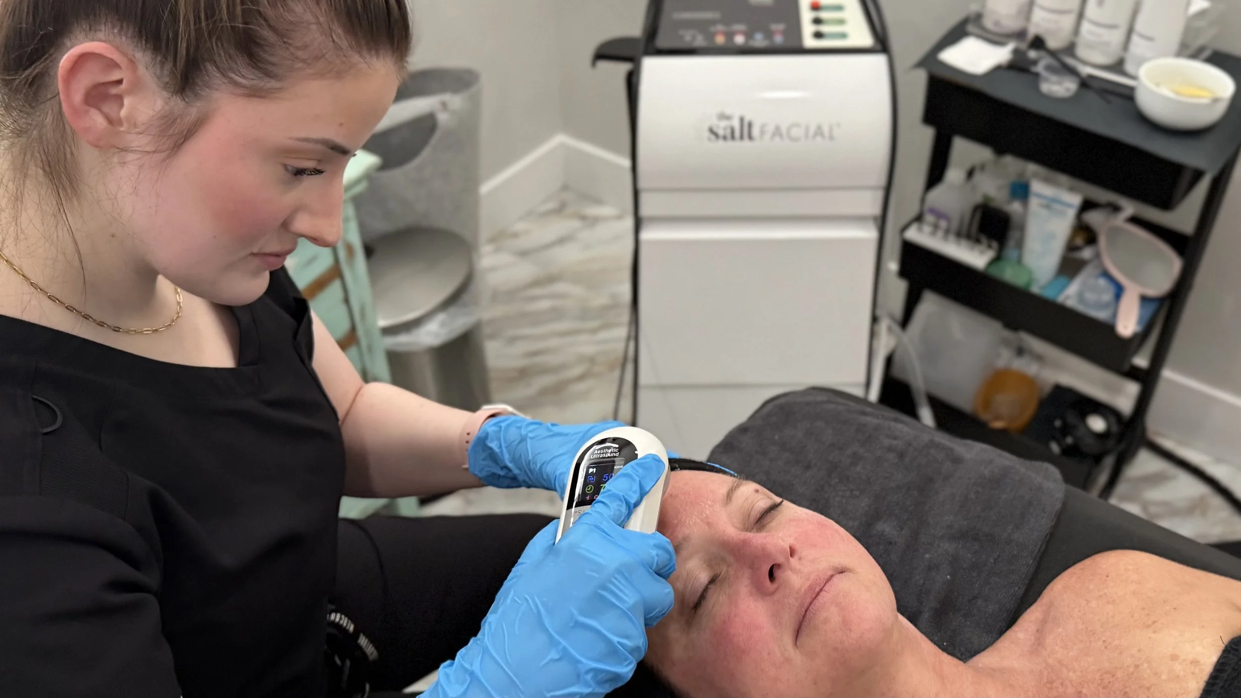 esthetician treating a patient with the aesthetic ultrasound device during The SaltFacial service
