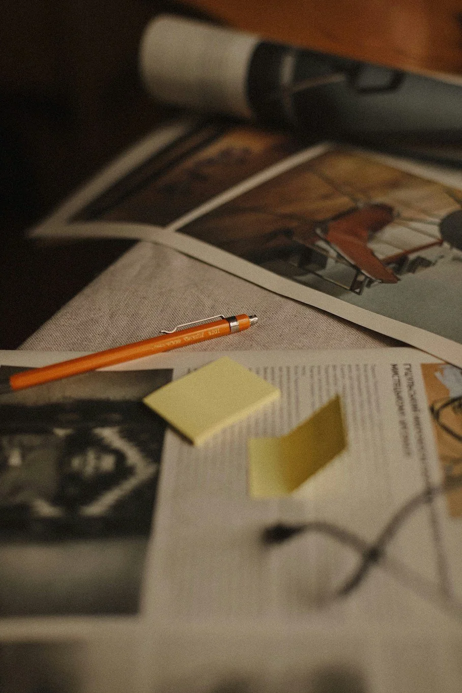 Close-up image of a desk covered with papers, a pen, and sticky notes
