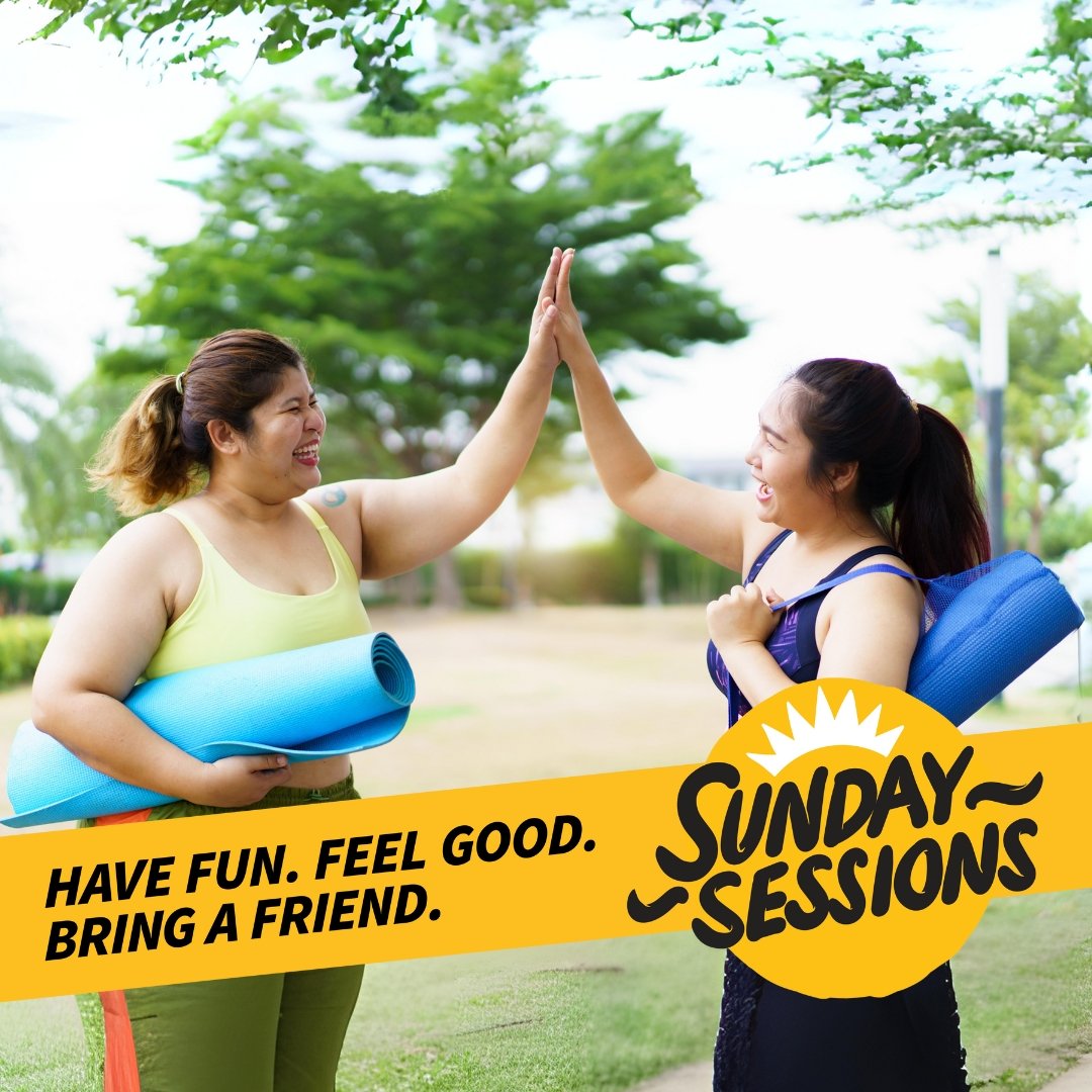 Two women holding yoga mats, smiling and giving each other a high five