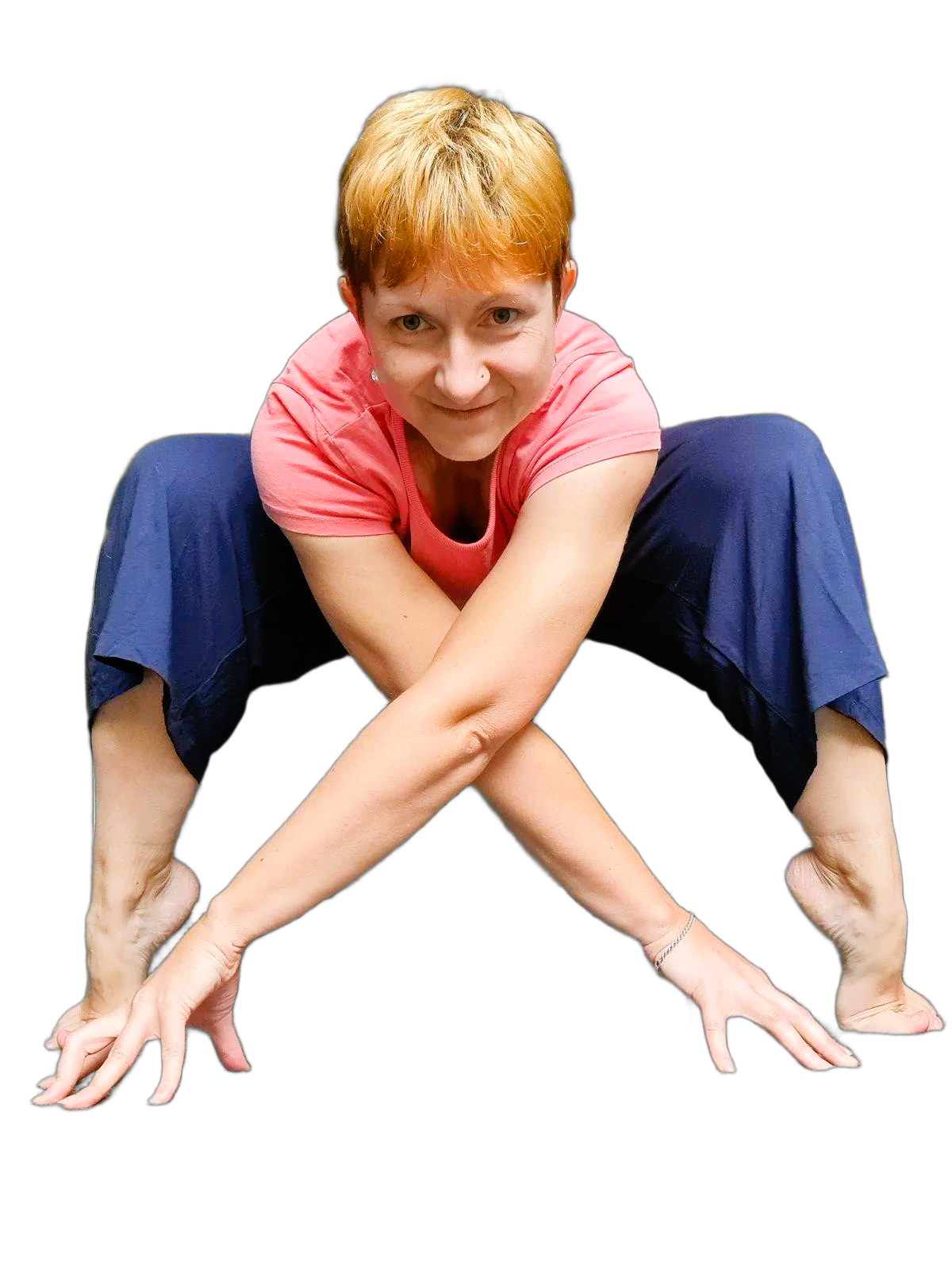 Woman wearing a pink shirt and navy pants in a yoga pose squatting down with bent knees and up on the toes, arms crossed in front with fingertips to the floor