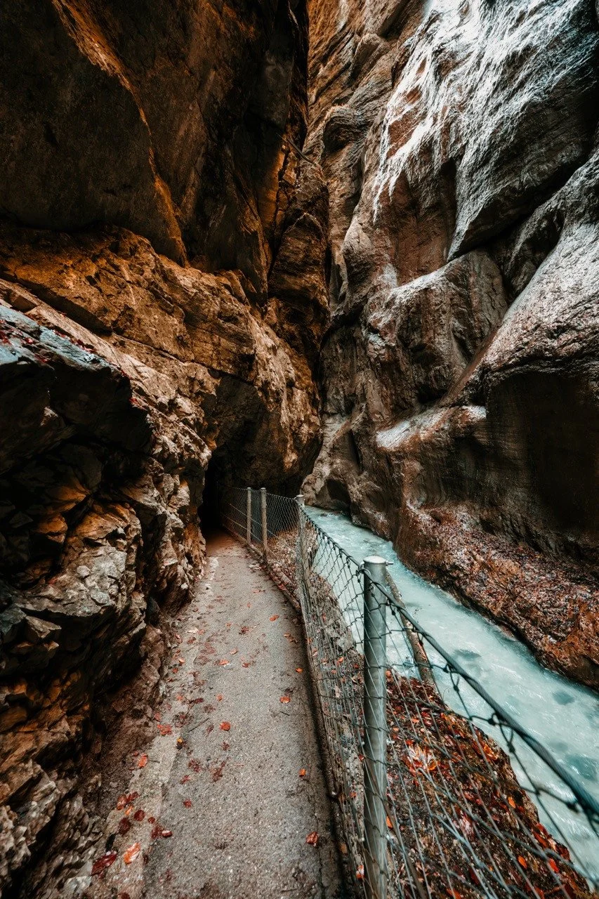 Narrow walking path beside the river beneath the rock walls of Partnach Gorge.