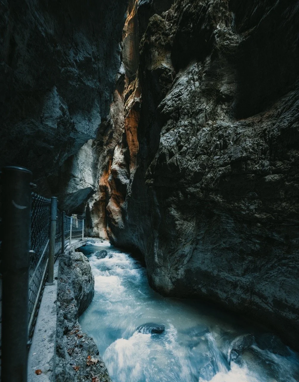Cool blue river flowing between the dark rock walls of Partnach Gorge.