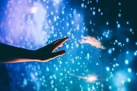 Two hands reaching towards each other with a background of glowing blue water droplets or bubbles.