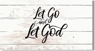 Decorative sign with the message 'Let Go and Let God' on a white wooden background.