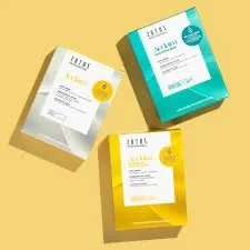 Three boxes of skincare or bath products, each in different colored packaging (white, blue, and yellow), placed on a yellow background.