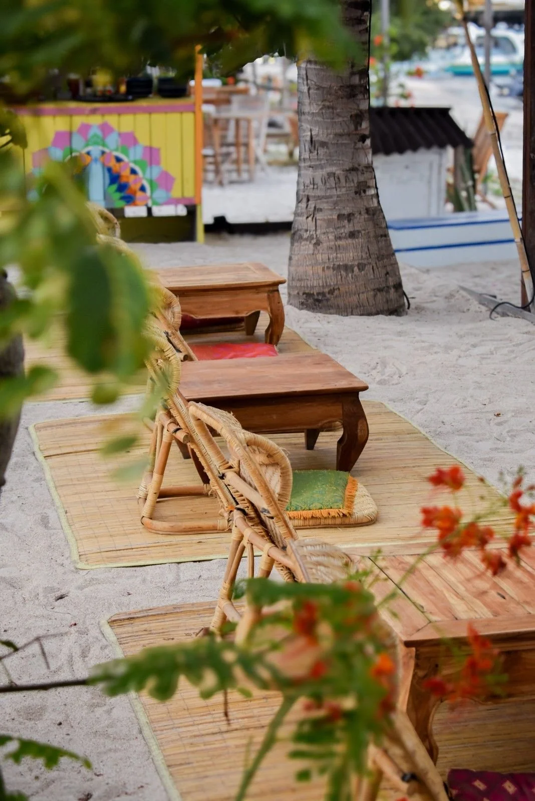 Beachfront seating with wooden tables, wicker chairs, and palm trees on Gili Trawangan