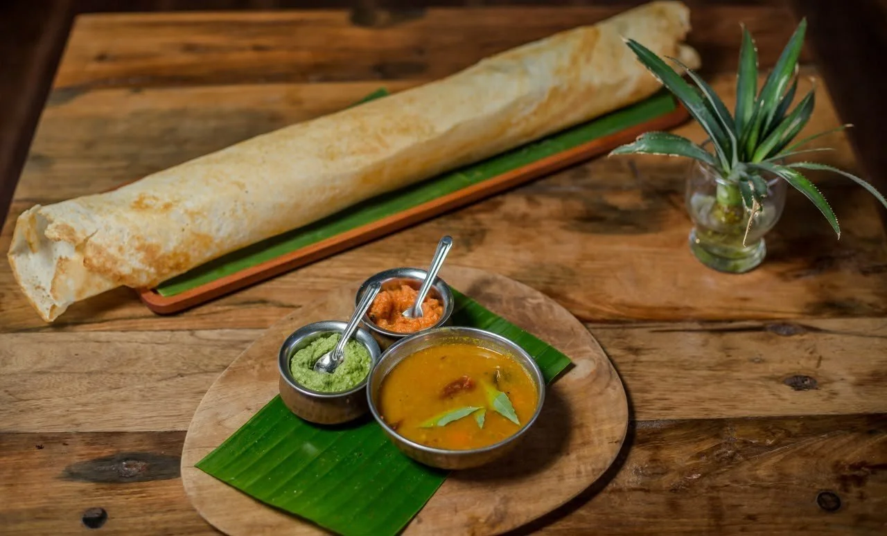 The Big Pesona Dosa, an oversized South Indian crispy dosa served with sambar and chutneys on a wooden table at Pesona Lounge Trawangan, Gili Trawangan.   Copy