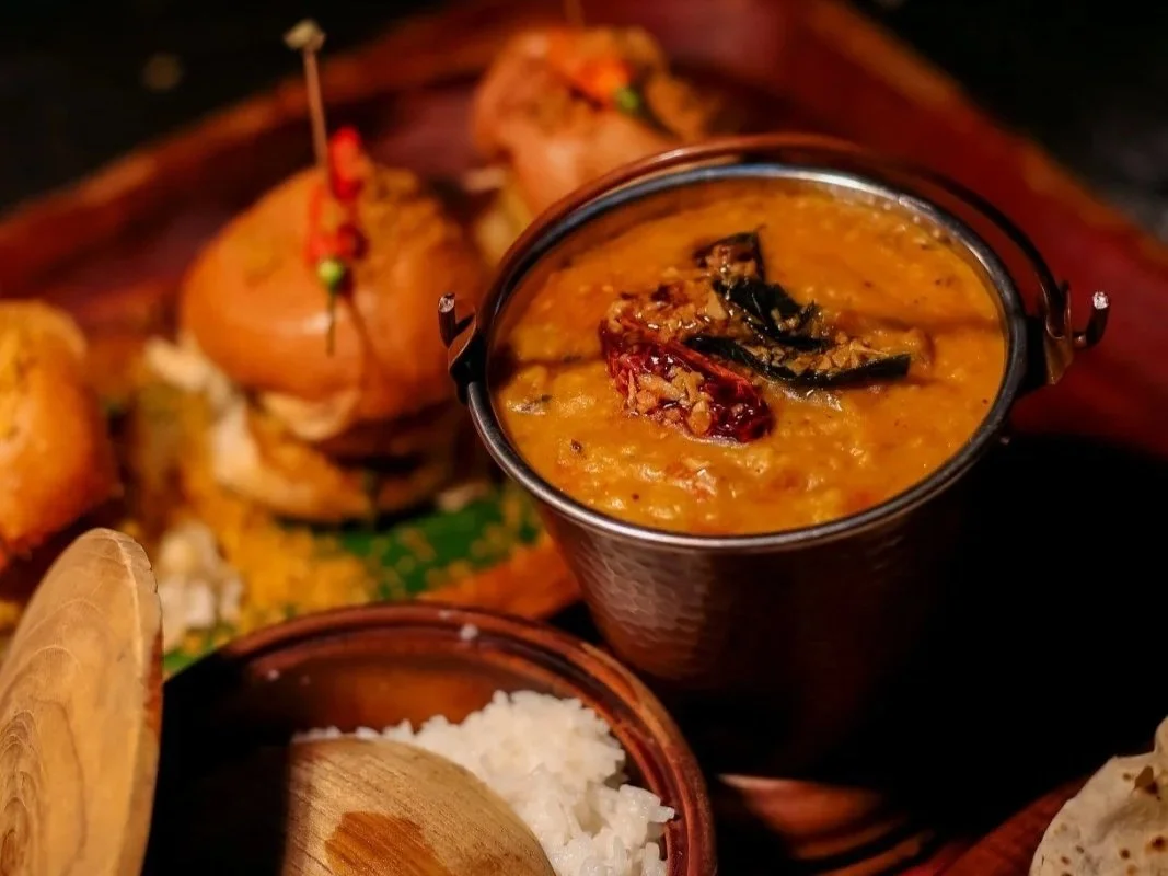 Indian curry served in a traditional metal bowl with bread and side dishes at Pesona Lounge Trawangan, a modern Indian and international restaurant in Gili Trawangan.
