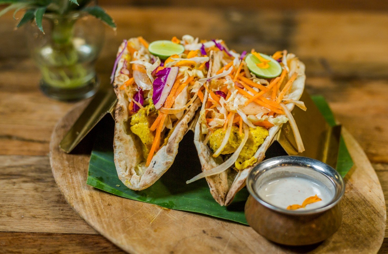Indian chicken tacos with naan bread, fresh vegetable slaw, and yogurt sauce served at an authentic Indian restaurant.
