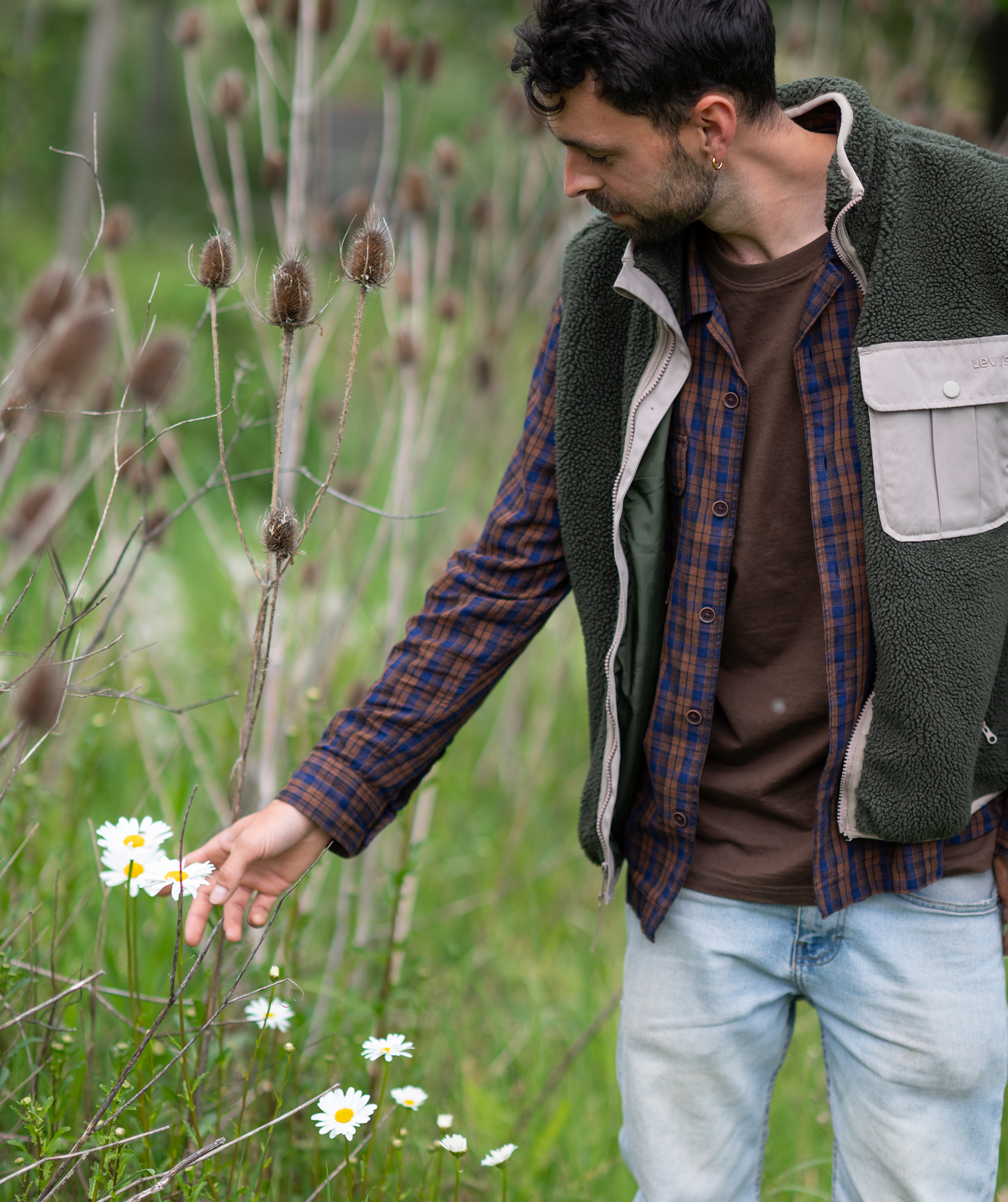 Man plukt witte bloemen in een veld met groene planten en bodembedekkers.