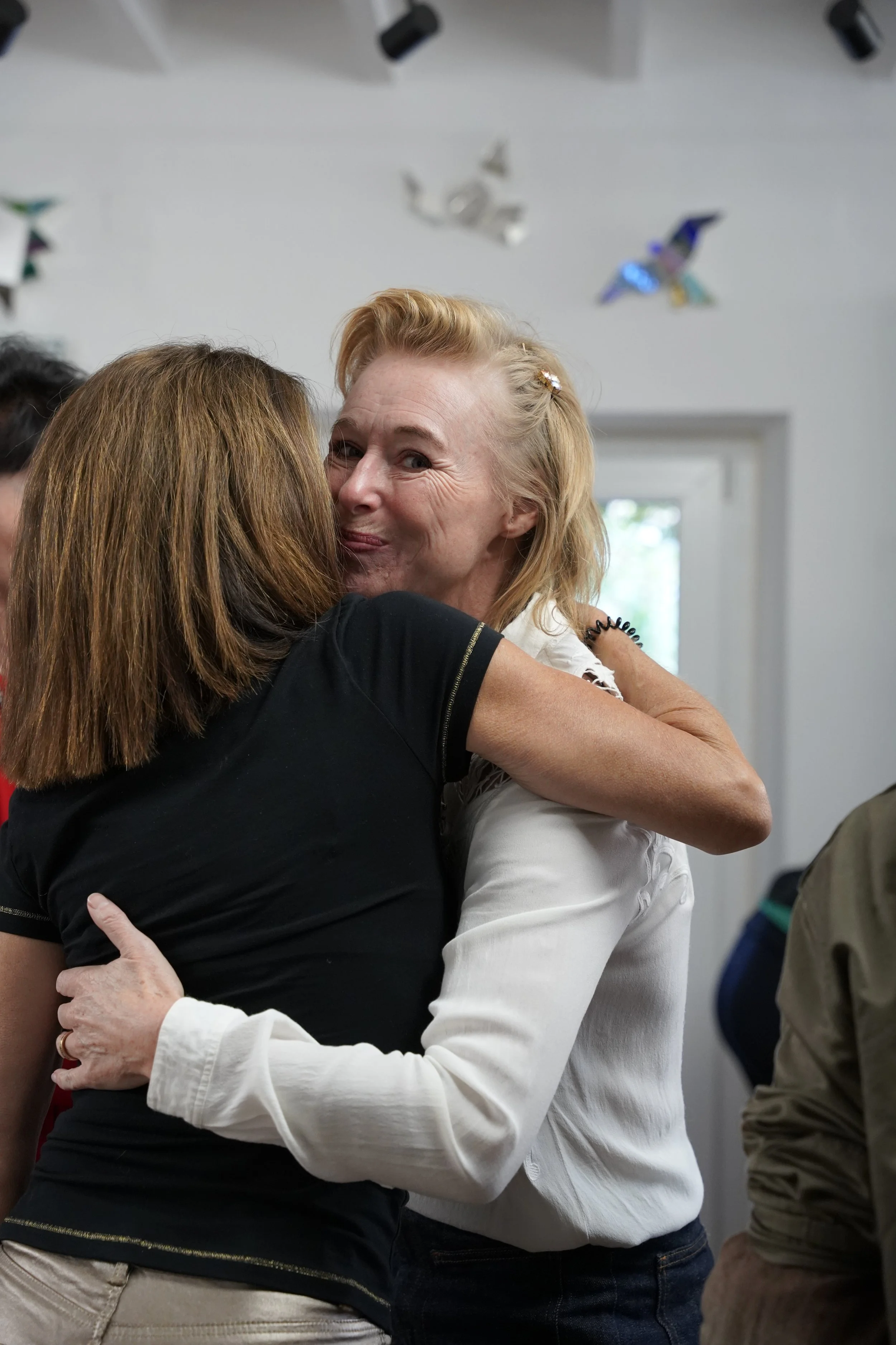 Two women hugging, one with blonde hair smiling and the other with brown hair.