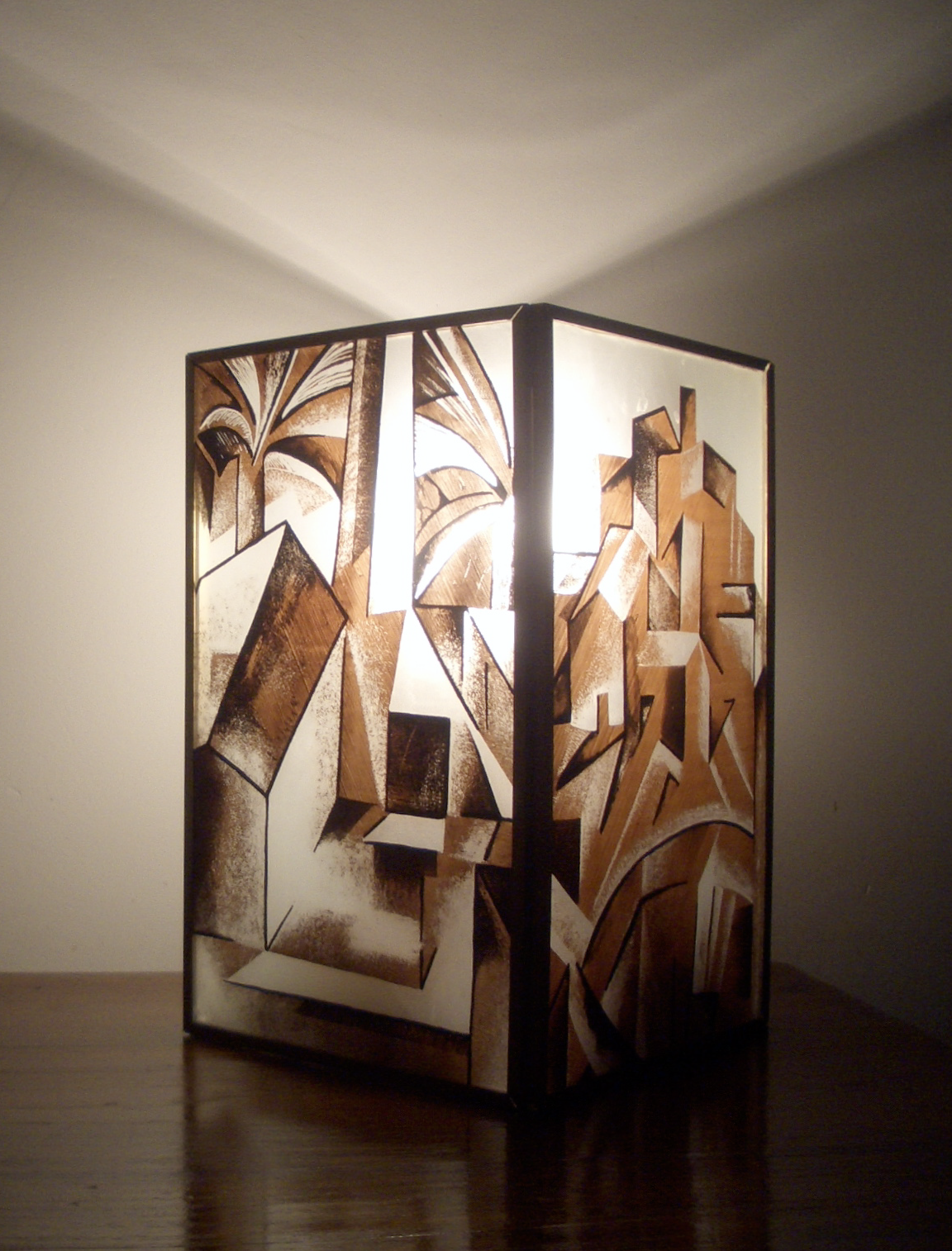 Wooden room divider with abstract geometric and botanical designs, lit from behind, in a minimalist room.