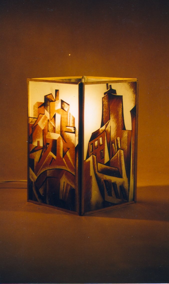 A decorative lamp with a geometric cityscape design emitting a warm glow, set on a flat surface in a dark room, with a starry sky visible in the background.