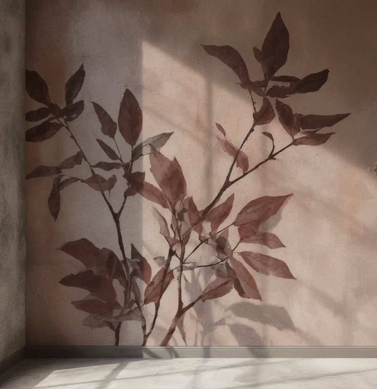 Shadow of a plant with multiple branches and leaves cast on a wall in a corner of a room.