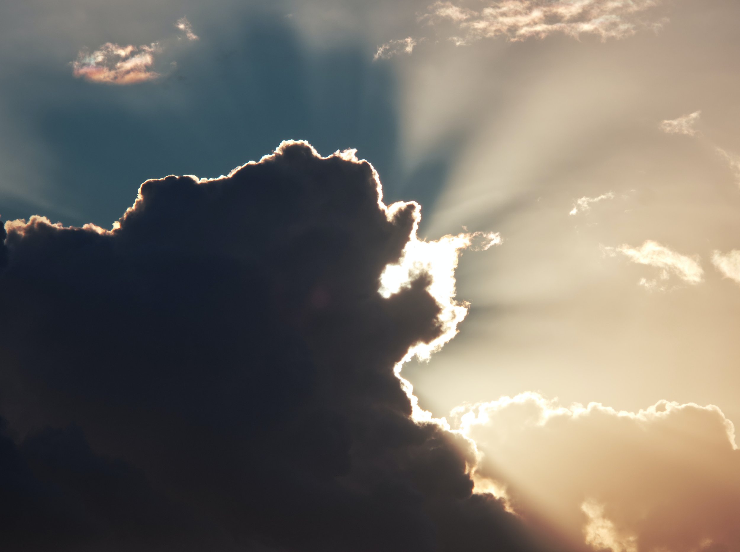 Sunlight breaking from behind a dark cloud with rays spreading across the sky, part of the natural imagery of The Oya Energy in Colchester and online.