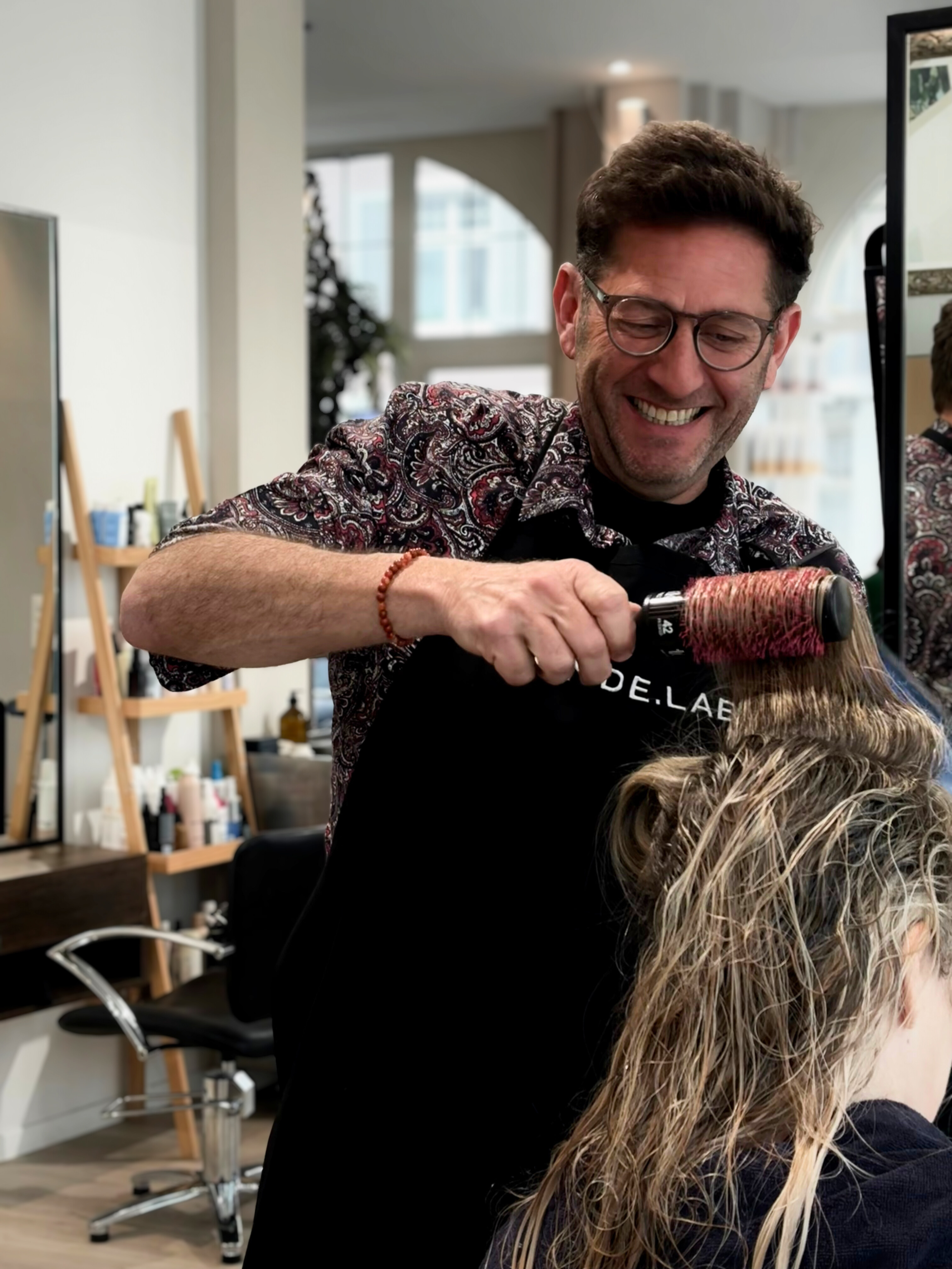 A smiling man cutting hair in a beautiful salon environment