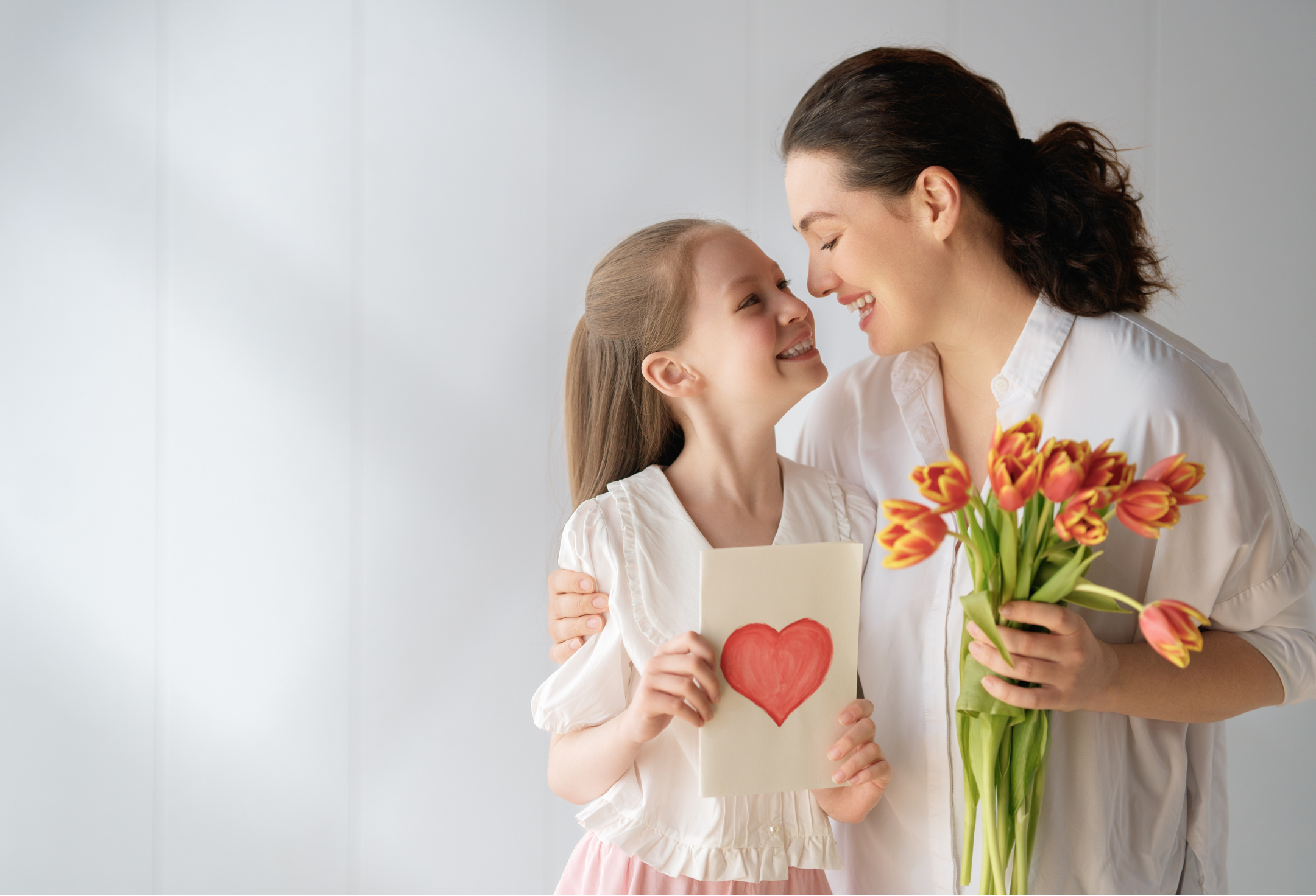 “Mother and daughter smiling and holding a card and flowers, showing warmth and connection in family relationships