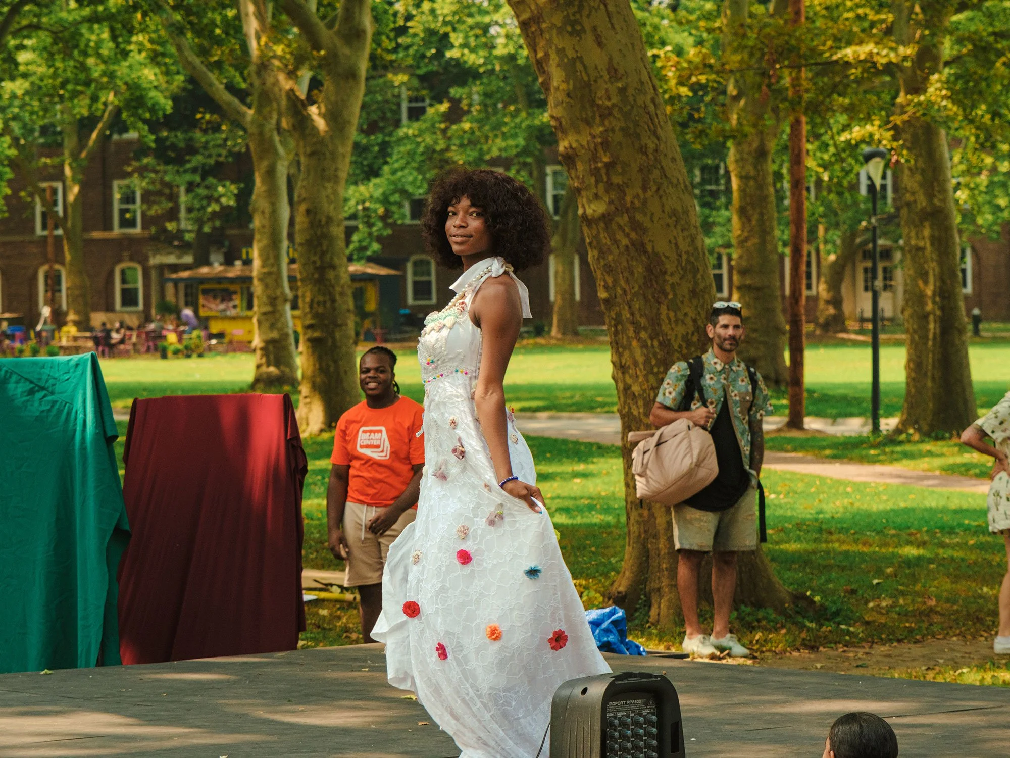 Young woman modeling a white dress covered in flowers at a youth fashion show