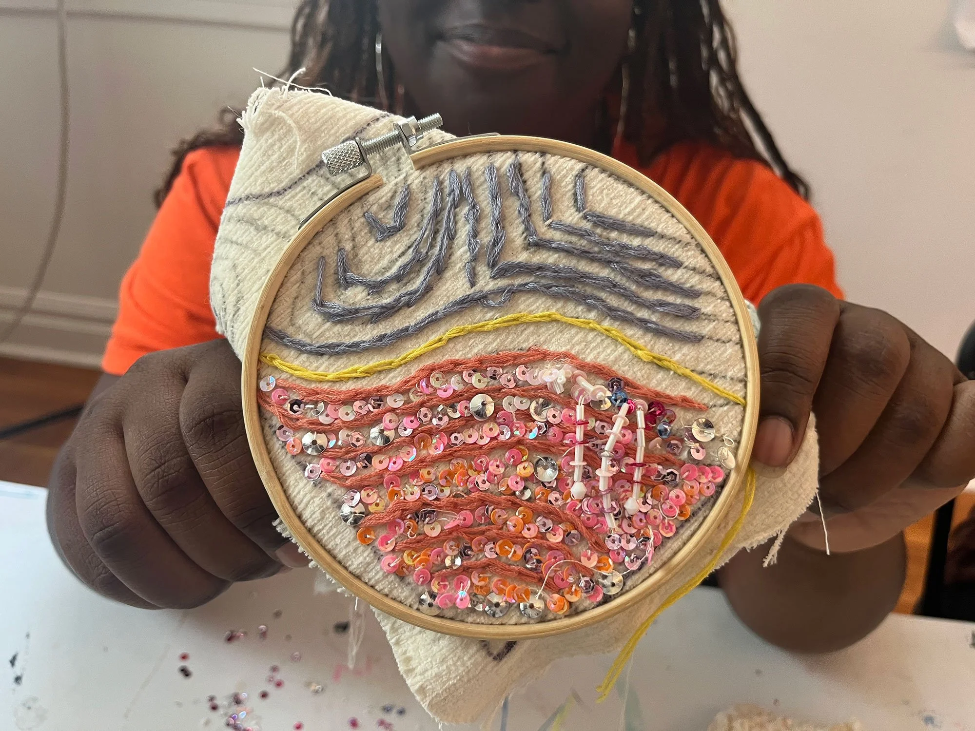Young girl holding up a ring with embroidery and beadwork on it