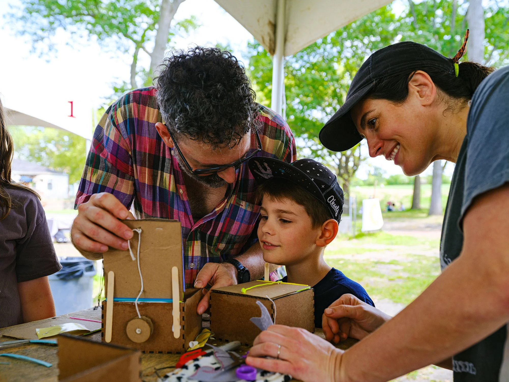 2 adults with a young boy constructing a project out of cardboard