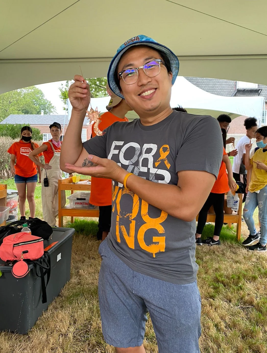 Bronx high school teacher holding a small sculpture while smiling outside at Beam Camp