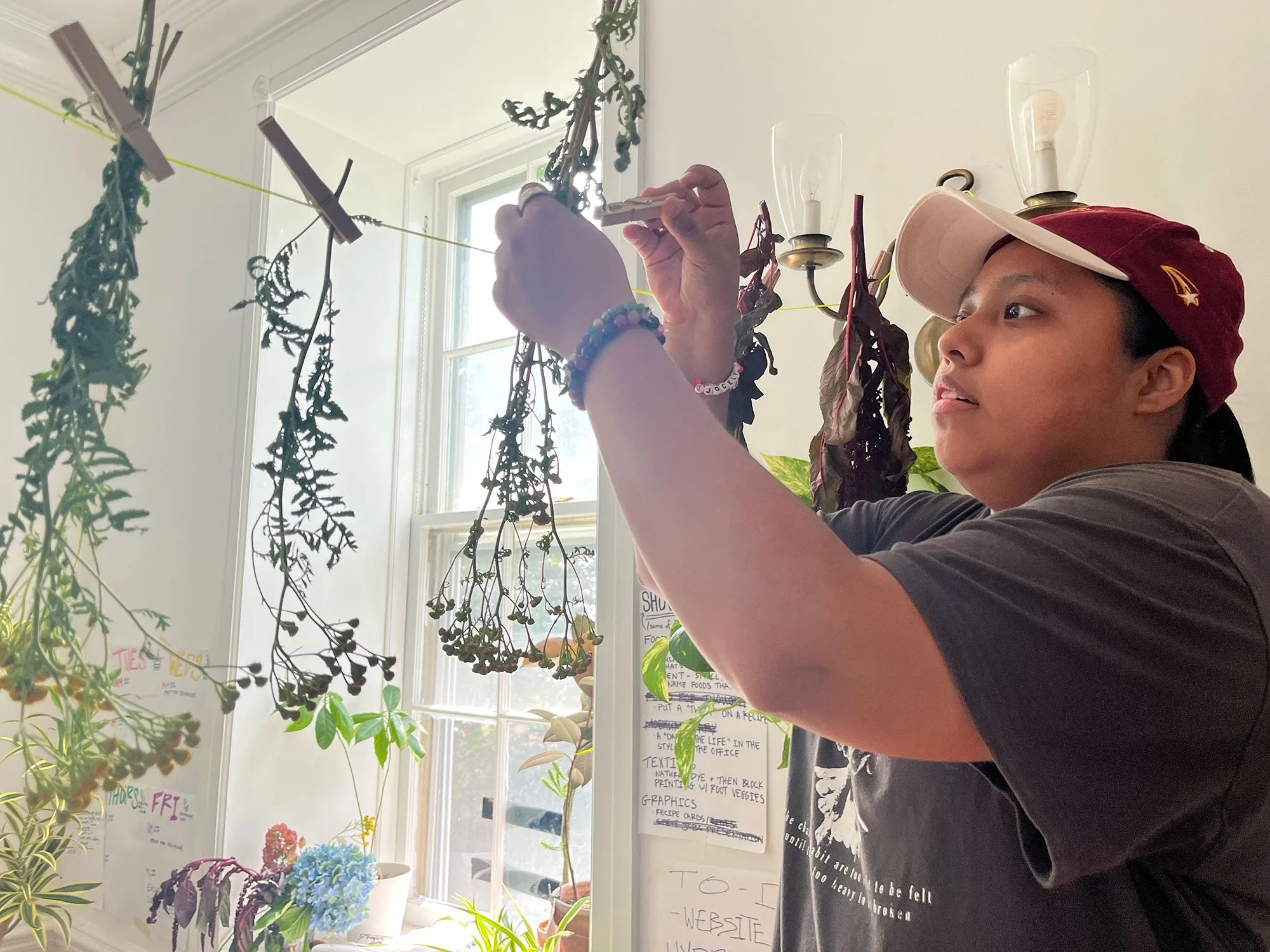 Student hanging herbs to dry on a clothes line at Beam Center's OtherWorlds Fair in 2024.