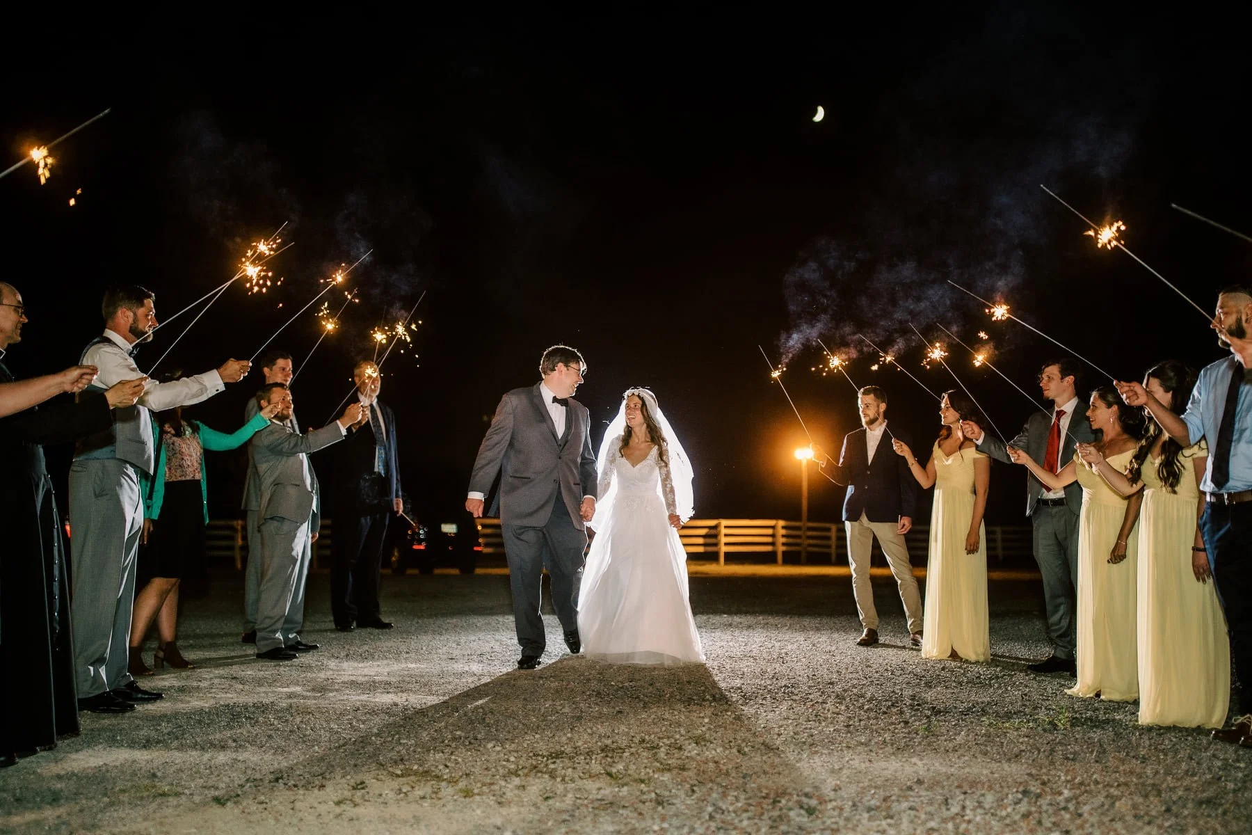 bride-and-groom-holding-hands-walking-bewtween-guests-holding-sparkerlers.jpg