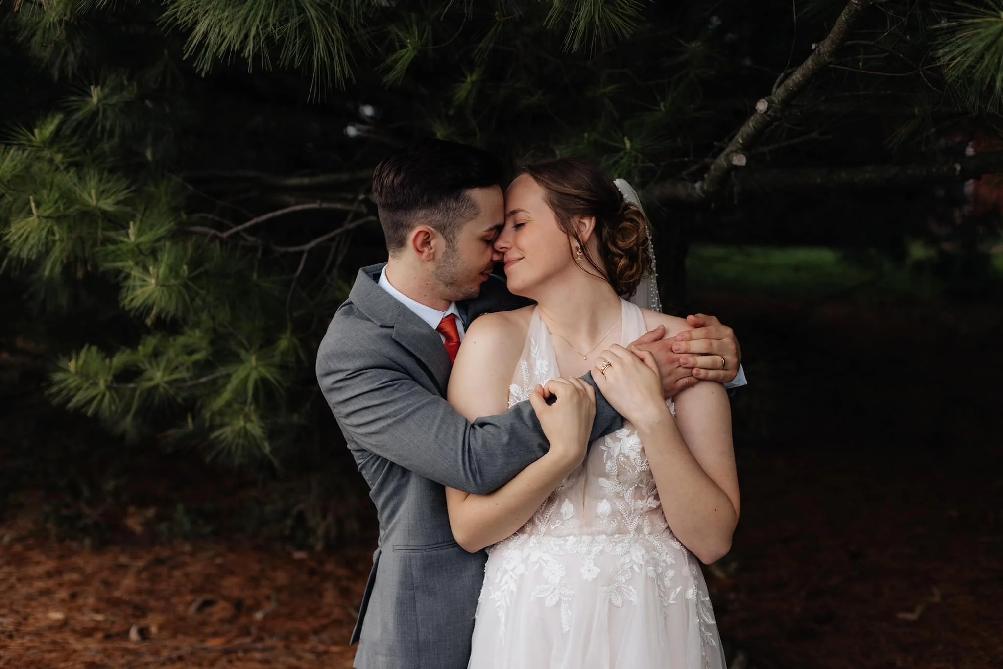 bride-and-groom-romatic-embrace-under-pine-tree.jpg