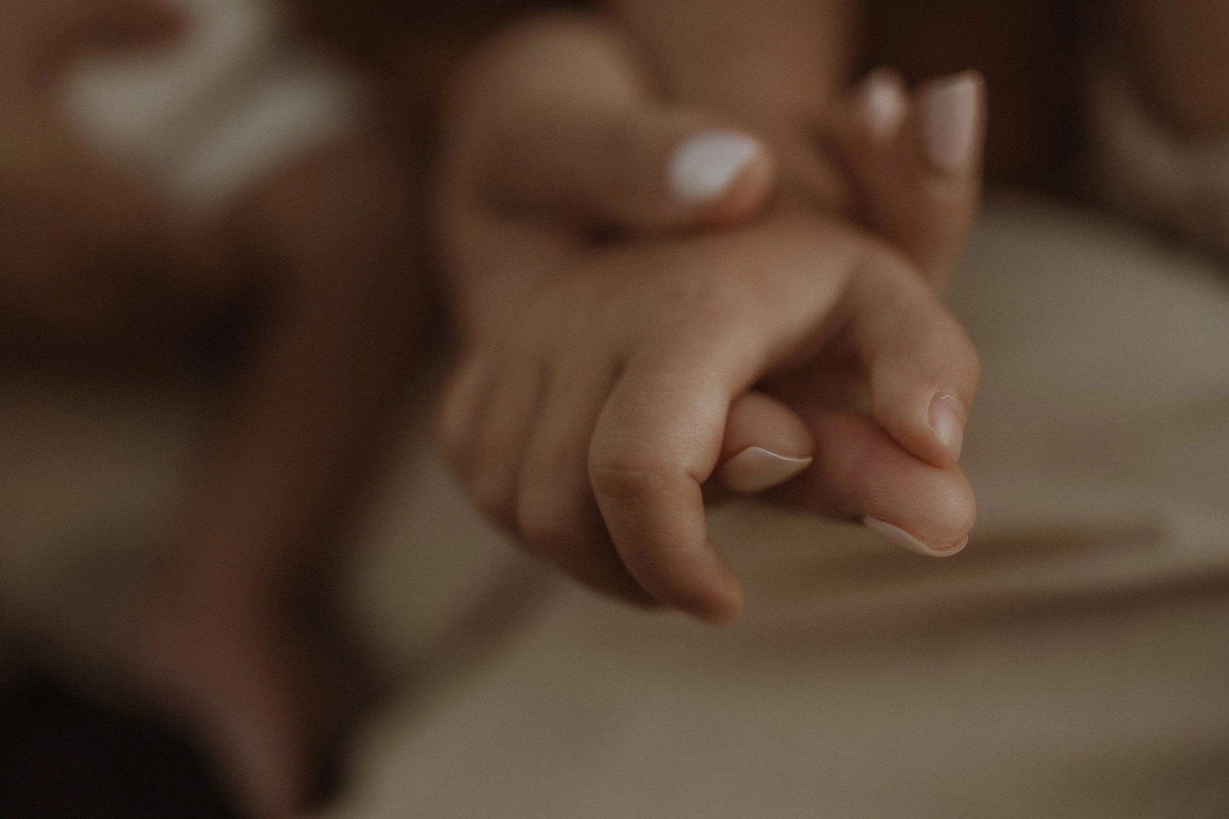 Close-up of two people holding hands, showing their fingers intertwined.
