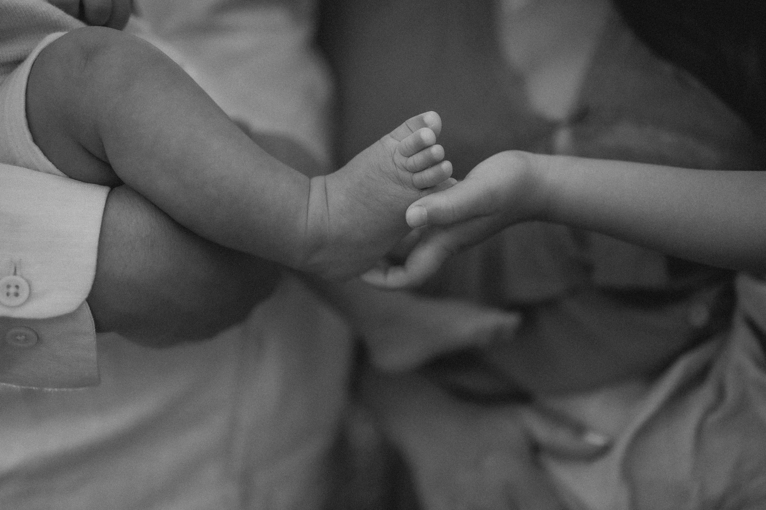 Close-up of a baby's foot being gently held by an adult's hand.