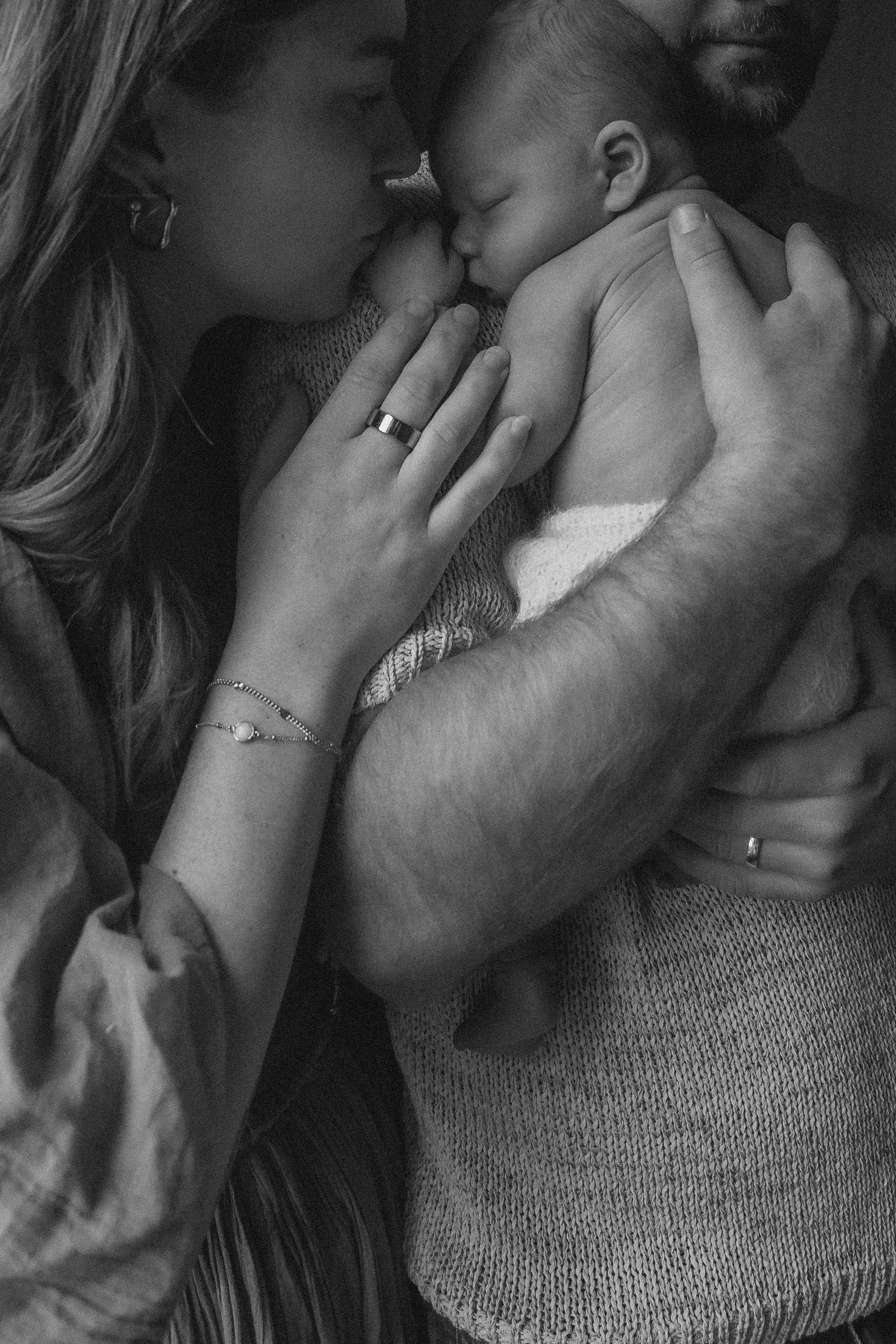 A natural black and white photo of connection between parents and their baby.