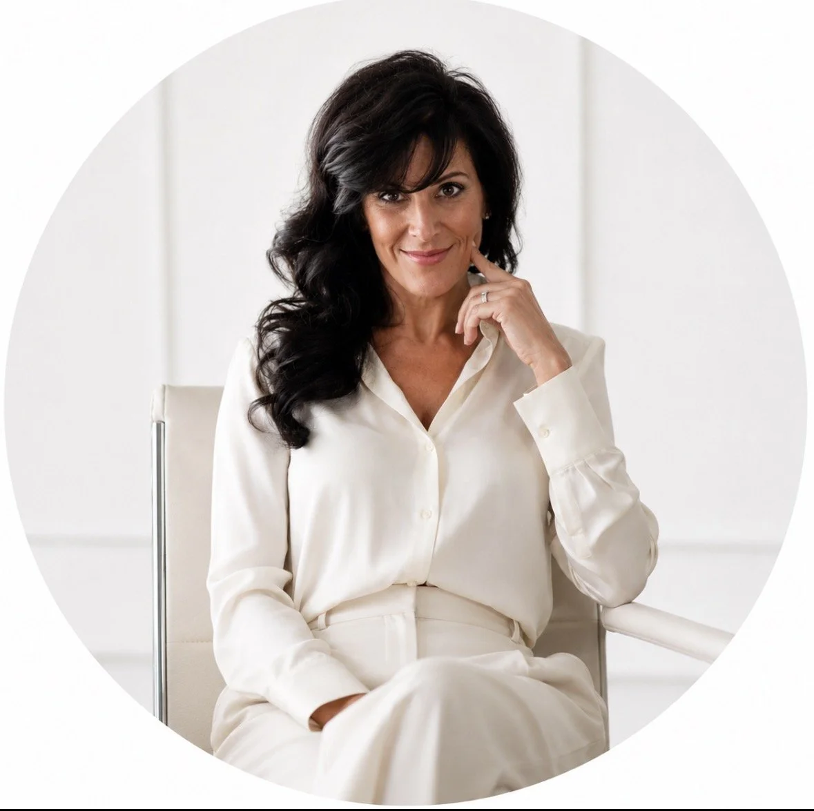 Portrait of a woman with dark brown hair, wearing a black blazer, smiling against a white background.