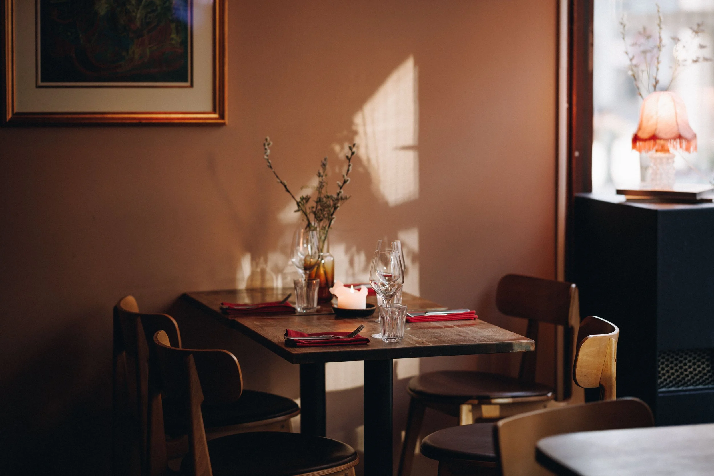 Bord dekket med blomster, tente lys og vin i ettermiddagssol hos Allmuen Bistro ved Torgallmenningen i Bergen.