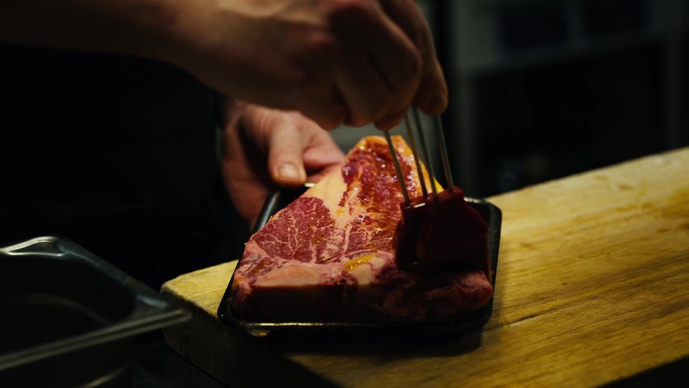 Rått, marmorert tørrmodnet storfekjøtt i brett, klart for grillen hos Allmuen Bistro