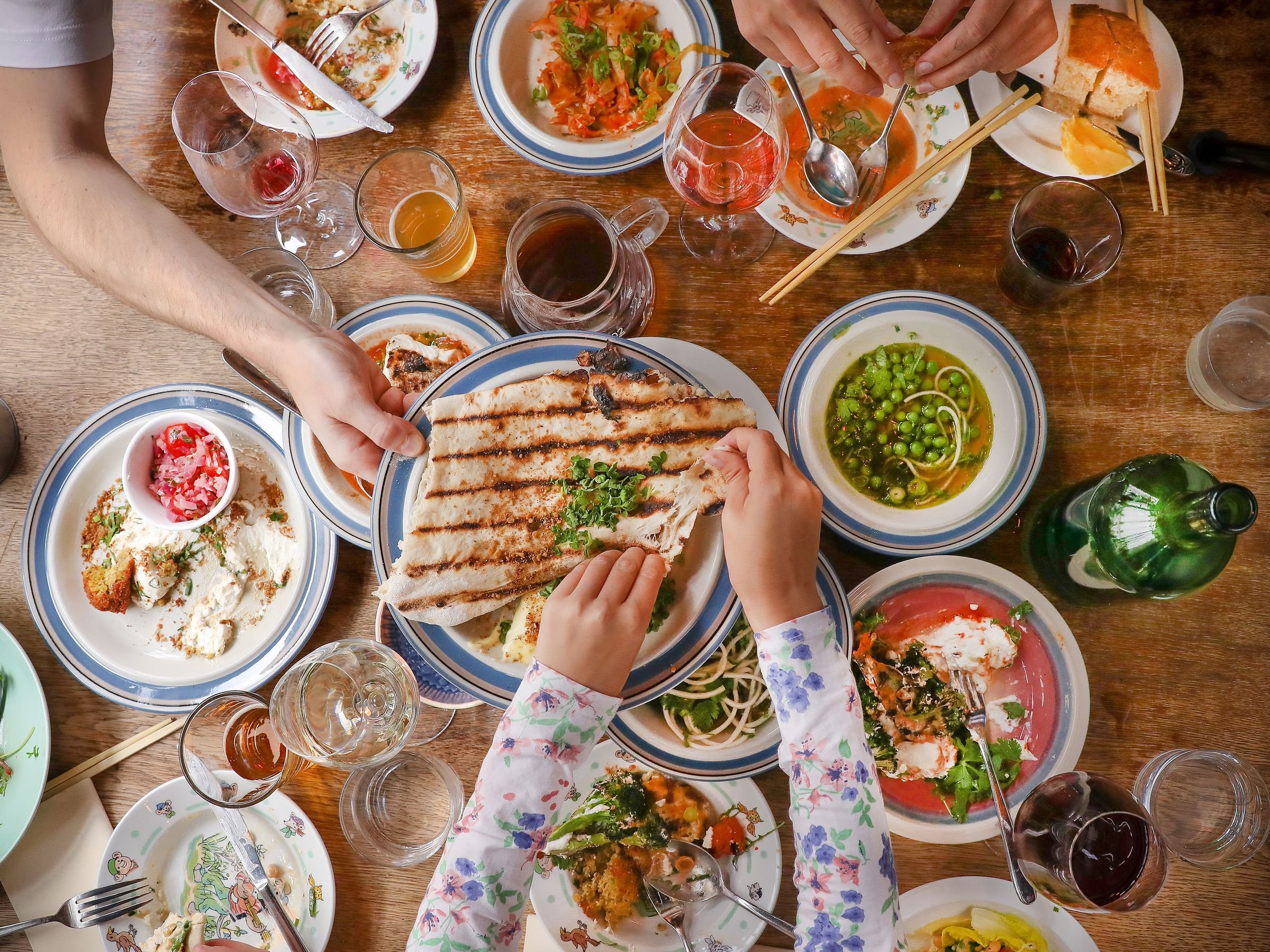 Venner og familie deler grillbrød og småretter rundt bordet hos Allmuen Bistro