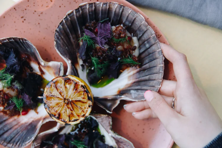 Scallops au gratin in their shells with herbs and grilled lemon at Allmuen Bistro
