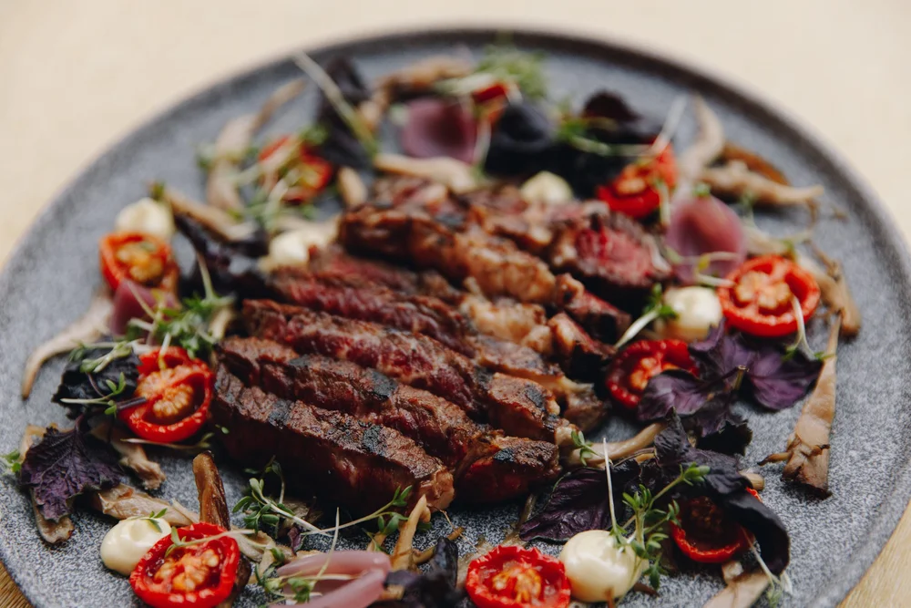 Grilled steak with tomatoes and herbs served on a platter at Allmuen Bistro in Bergen