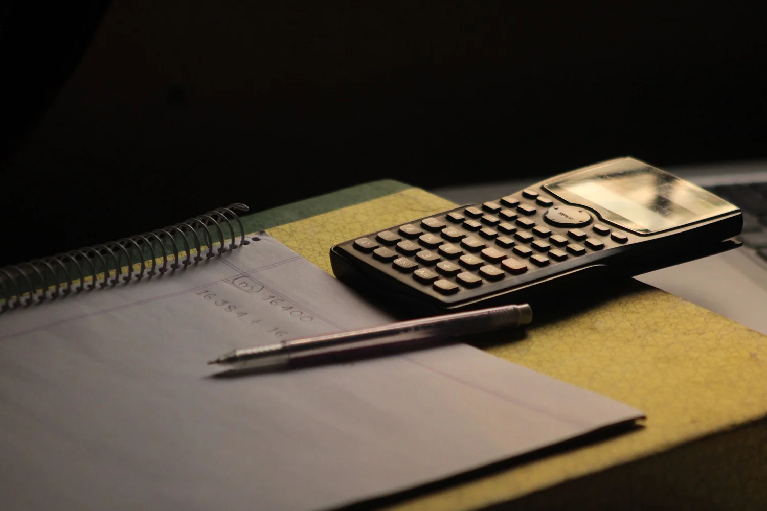 Calculator, notebook and pen on a desk