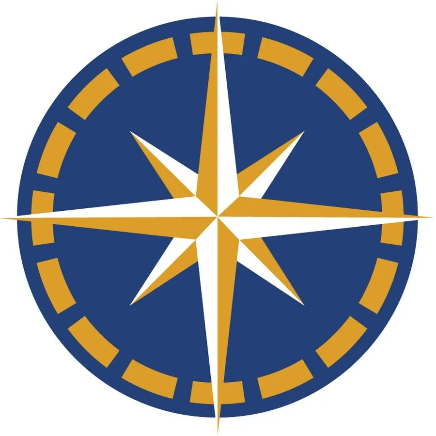 A compass rose with a navy blue background, gold and white points, and gold markings around the edge representing E/V Nautilus