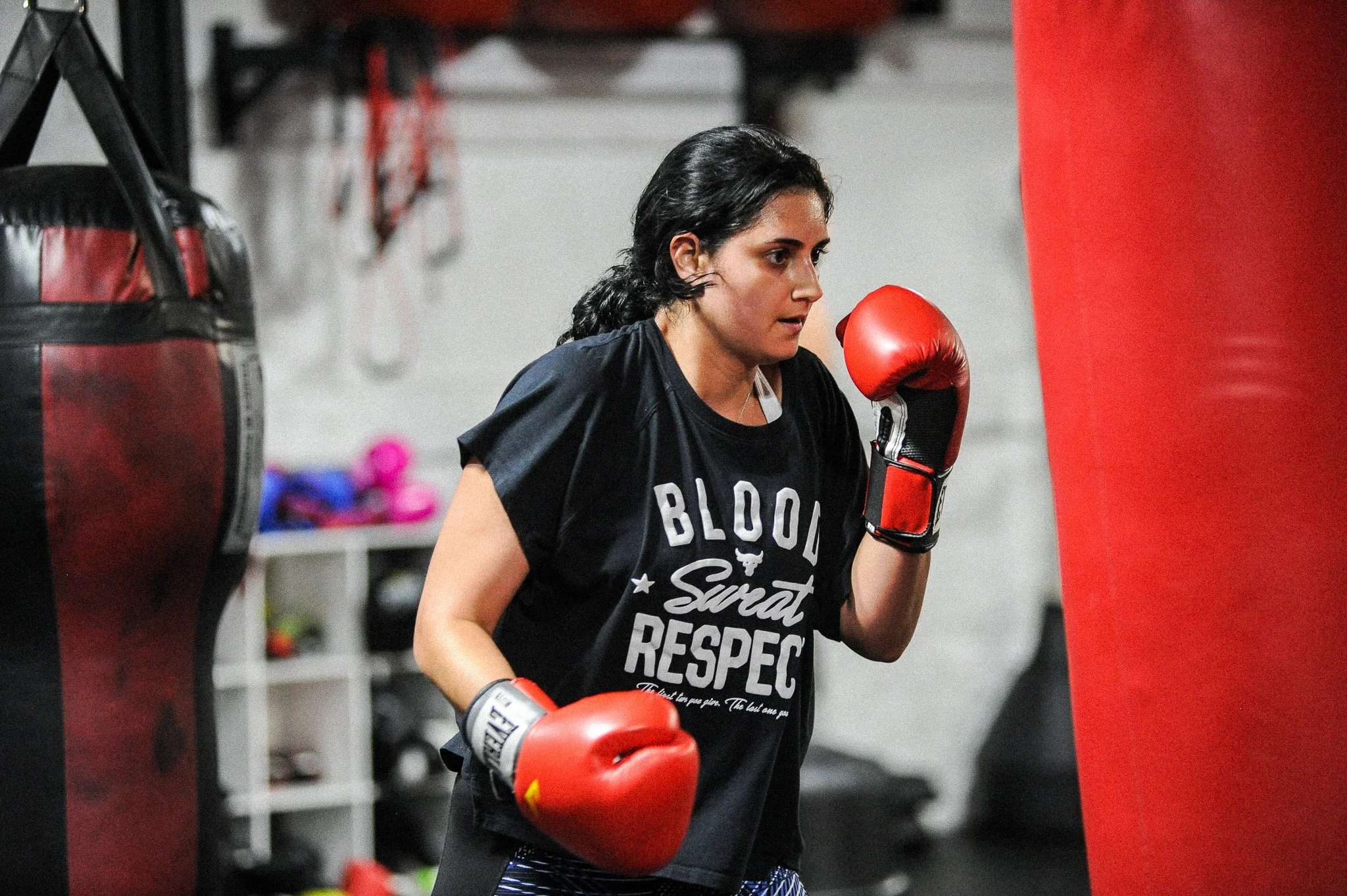 A woman wearing boxing gloves and athletic clothing training with a punching bag in a gym