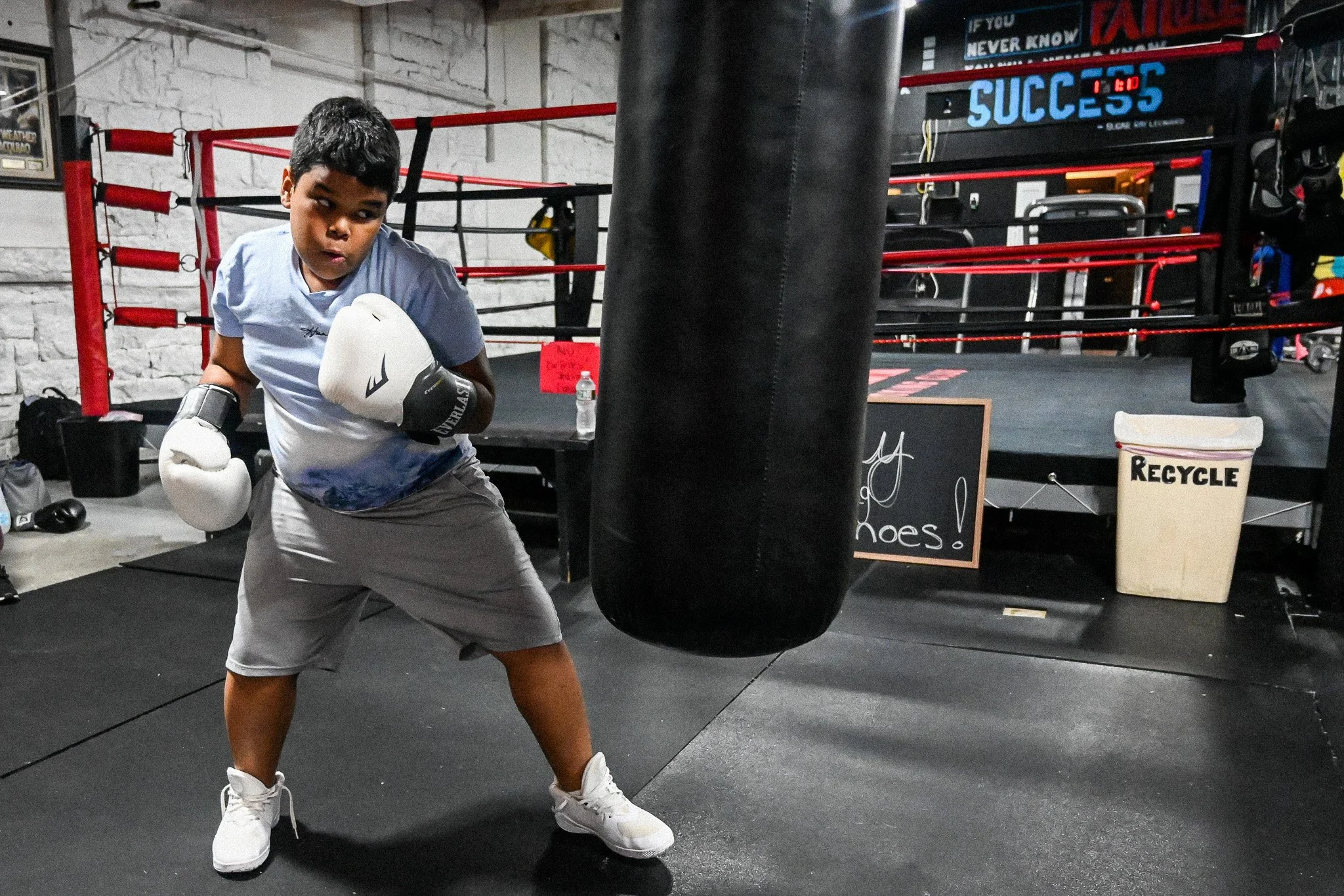Young boy punching boxing bag at Upperkuts Boxing Club gym in Massachusetts