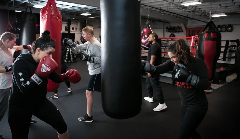 Females punching boxing bag at gym