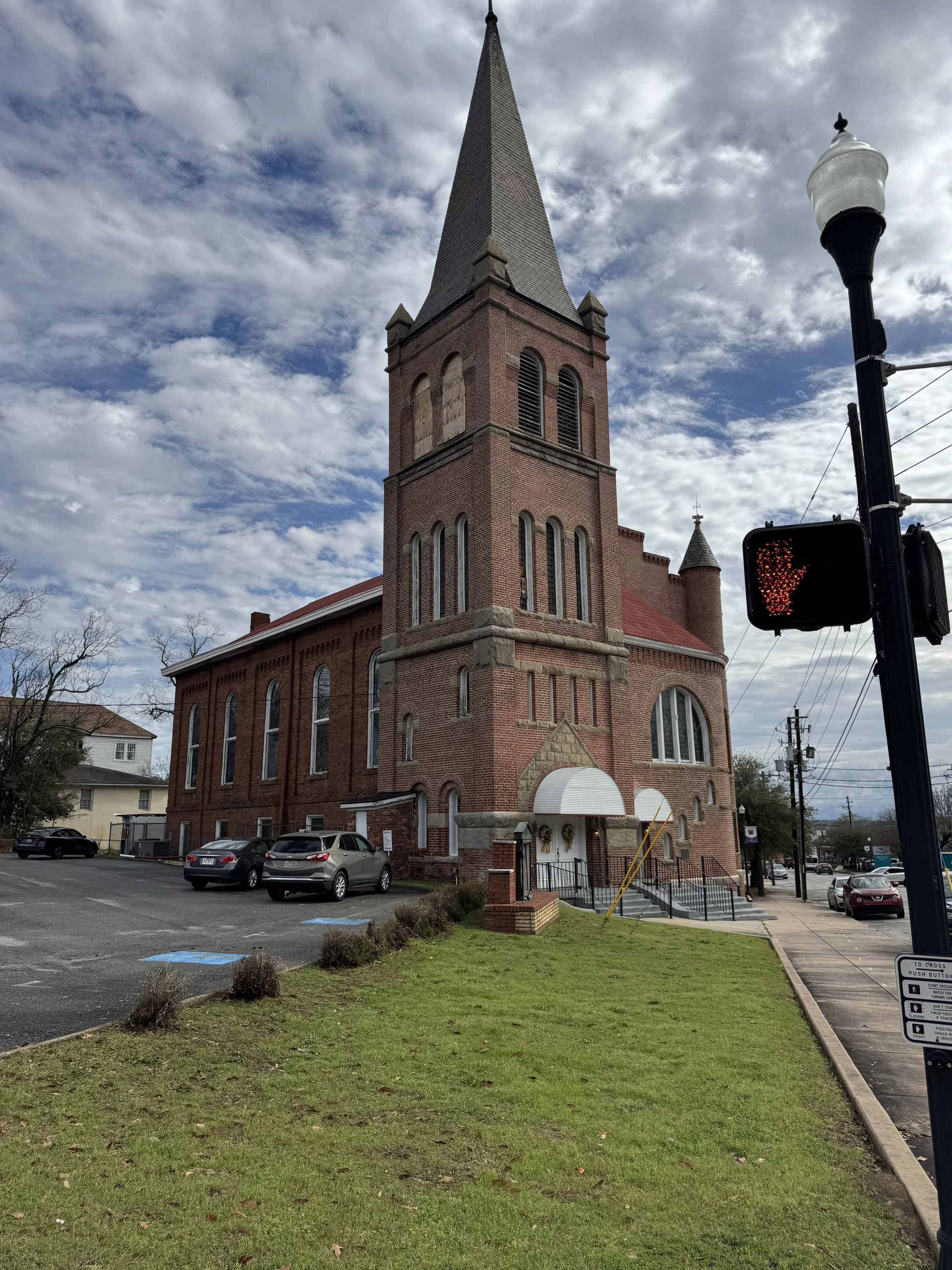 A photo of a cbrick hurch featuring a tall bell tower.