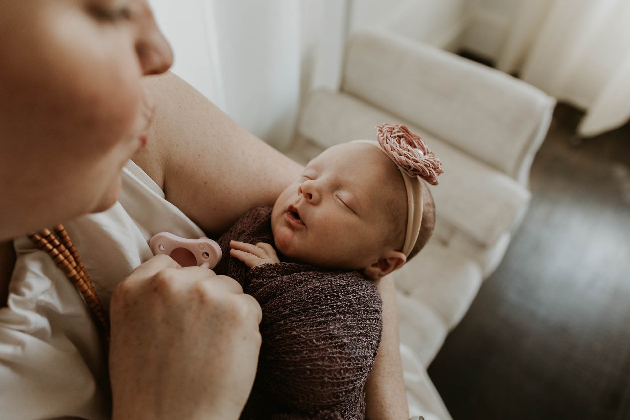 This baby is cozy and happy in her mother's arms during her newborn photography session.