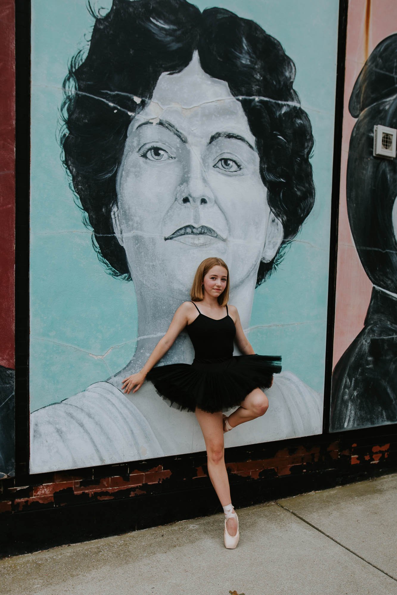 A ballet dancer from Twin Cities School of Dance in Bloomington, Illinois, stands in front of a mural of Minnie Saltzman-Stevens.