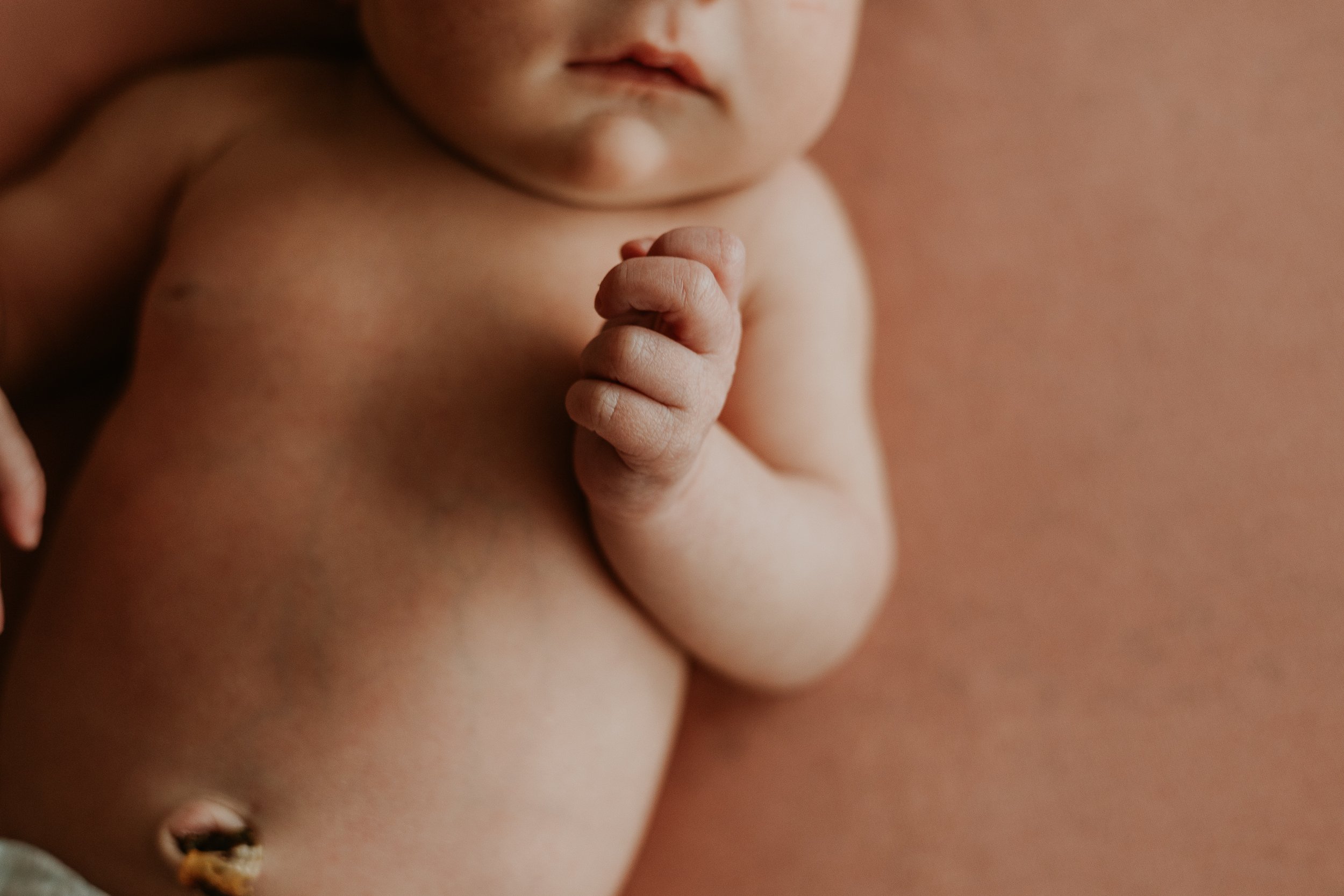 A newborn's clenched fist, little lips, and dried umblical cord.